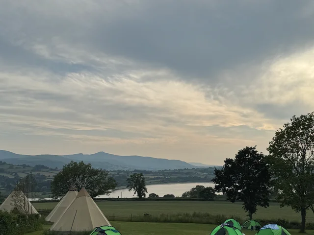The expedition campsite beside a lake, with tents and tipis