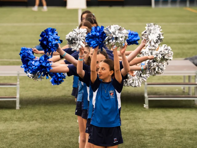 Students cheering with blue and silver pom-poms