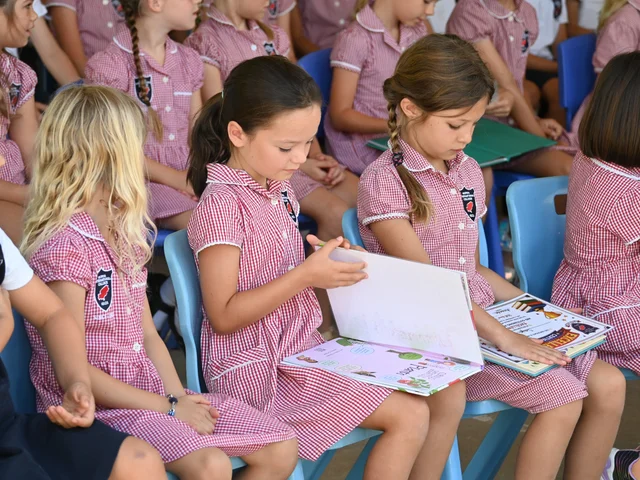 Children looking through their work during the end-of-year celebration