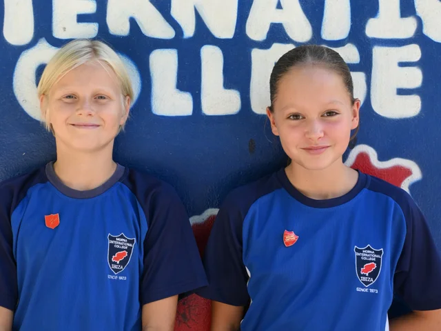Two House Captains wearing their house badges by the school mural