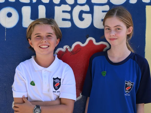 A pair of House Captains in front of the school mural