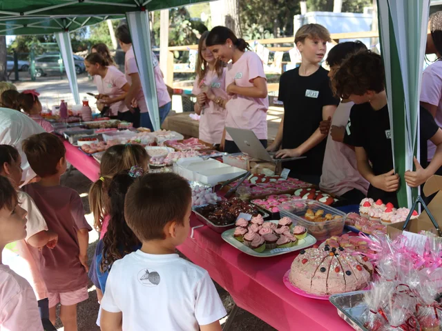 Younger pupils queueing at the bake sale tables while older students serve