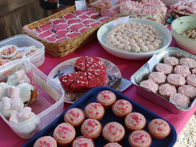 Pink cupcakes, meringues and a heart-shaped cake on the bake sale table