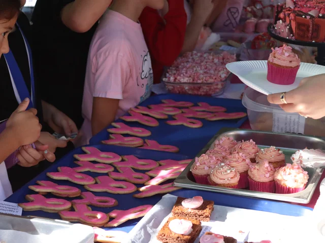 Children reaching for pink ribbon biscuits and cupcakes