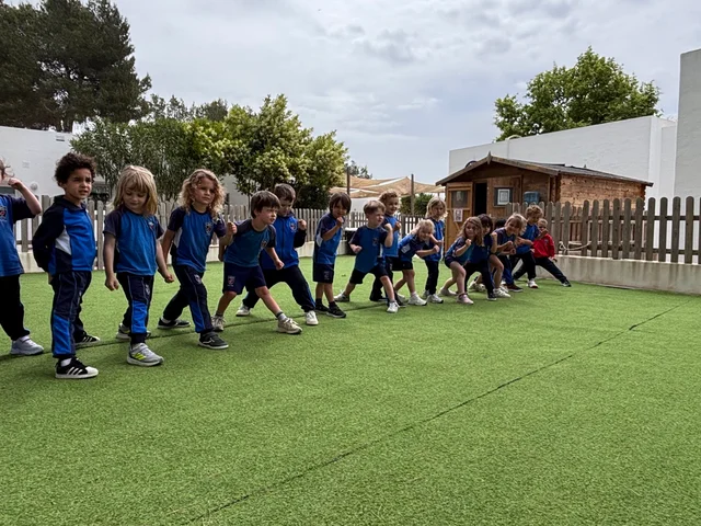Early Years children lined up on the artificial grass for a PE lesson