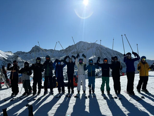 Students in ski gear lined up on the slopes with mountains behind