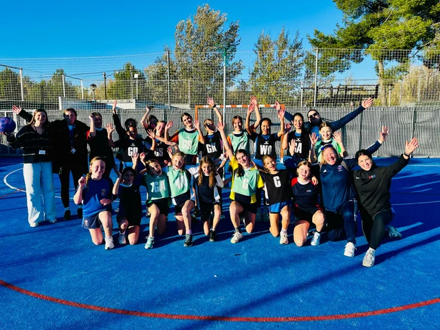 Morna's netball players celebrating on a blue court in Barcelona