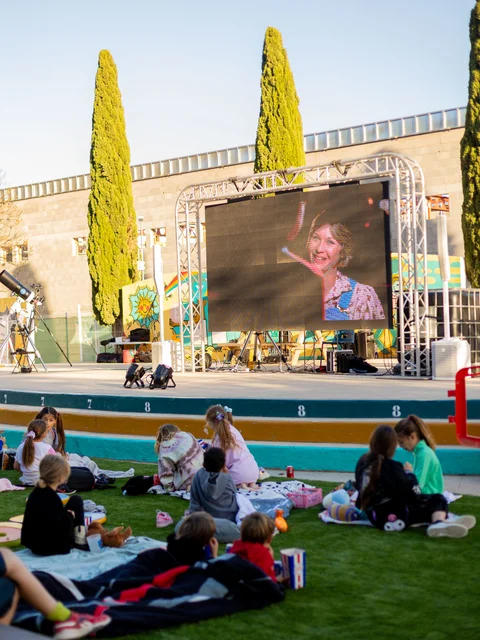 Children on the grass in front of the big outdoor screen