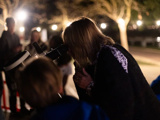 A visitor looking through a telescope after dark
