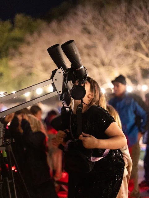 A girl looking up through large astronomy binoculars
