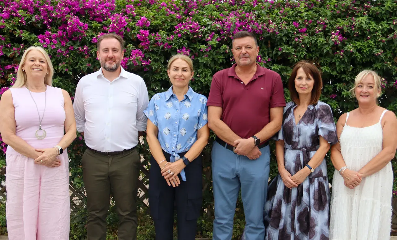 Morna's Senior Leadership Team standing together in front of bougainvillea on the campus