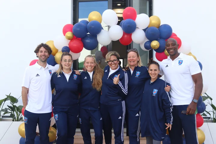 The Morna PE team in their school sports kit, in front of a balloon arch at the school entrance