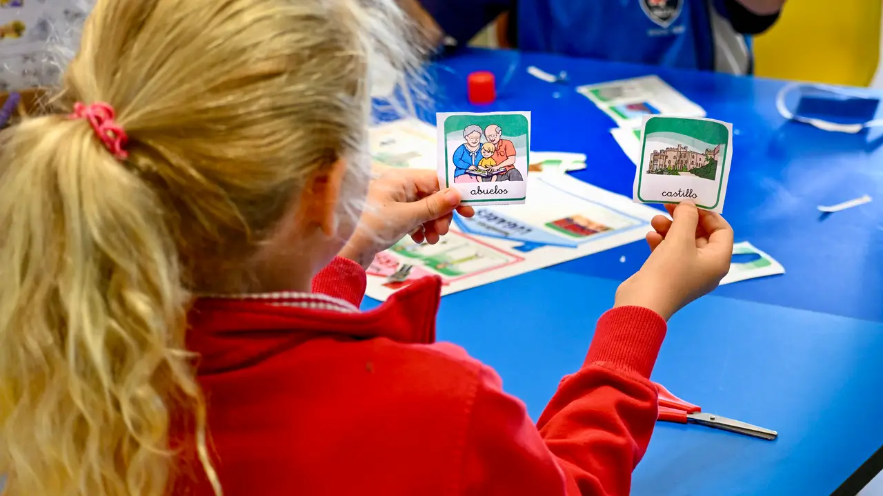 A Primary pupil holding up two picture vocabulary cards during a Spanish lesson